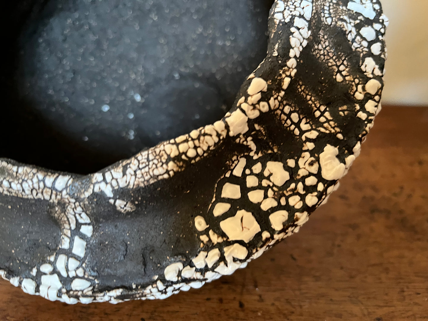 Large folded lip black stoneware bowl with white crawling glaze